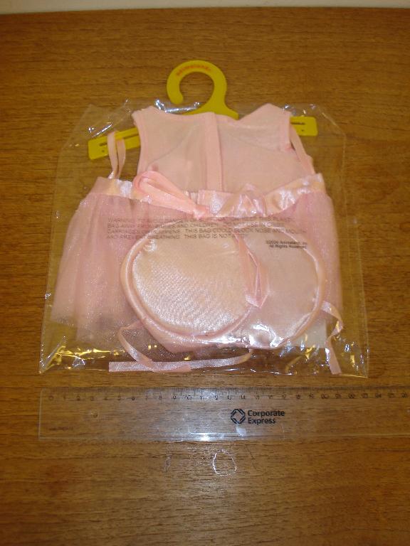 Varen fremstår som et sæt lyserødt dukke/bamsetøj bestående af sko, skørt og body, ophængt på plastbøjle og pakket i plastpose til detailsalg. 

Skoene er med en rund sål ca. 9 cm. i diameter af satinlignende tekstilmateriale og overdel af samme tekstilmateriale og med snore (som balletsko) til at snøre, men også med elastik rundt langs kanten på overdelen.

Skørtet er fremstillet af tyl-agtigt tekstilmateriale. Højden er ca. 10 cm og bredden 20-25 cm. Der er gennemgående åbning bagpå, som lukkes med velcro. 

Bodyen er fremstillet af satinlignende trikotagemateriale. Højden er ca. 21 cm og bredden ca. 17 cm. Der er påsyet en rose fortil. Der er velcrolukning bagtil foroven og åbning længere ned (passende til halen på en bamse).