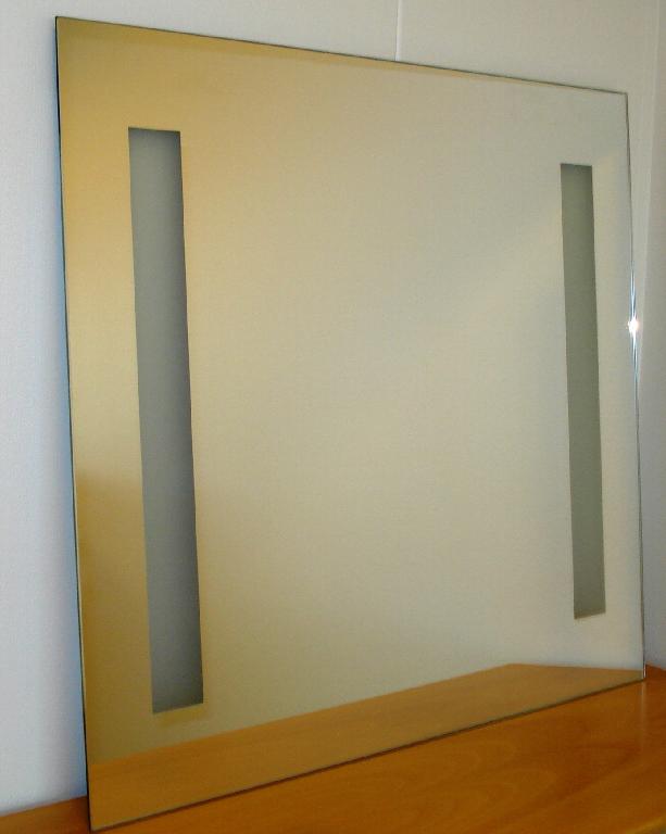 Varen fremstår som et spejl med elektrisk lys.

Produktet er sammensat af 2 dele, som er
• et glasspejl med en størrelse på ca. 70 cm x 65 cm. I spejlet er 2 matslebne rektangulære glaspartier hver på ca. 5 cm x 48 cm, beregnet for gennemtrængning af lys.
• et elektrisk lysarmatur i hvidmalet metalkasse og med 2 stk. lysrør.

Produktet samles ved, at metalkasse med lysarmatur monteres på en væg. Glasspejlet monteres på armaturet ved hjælp af beslagene bag på glasspejlet, der isættes armaturet. De 2 lysrør i armaturet er placeret bag de matslebne glaspartier i spejlet.

Produktet fremstår som et spejl med elektrisk lys gennem de matslebne glaspartier.