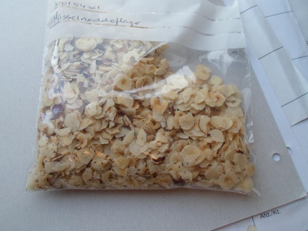 100% hasselnøddekerner

Produktet betegnes 100% hasselnøddekerner og fremstår som flager snittet af hasselnøddekerner. Den brune hinde har ikke været fjernet efter nøddernes afskalling, dette er tydeligt at se hvor rester af den brune hinde som har løsnet sig under snitningen af kærnerne er blandet sammen med flagerne.