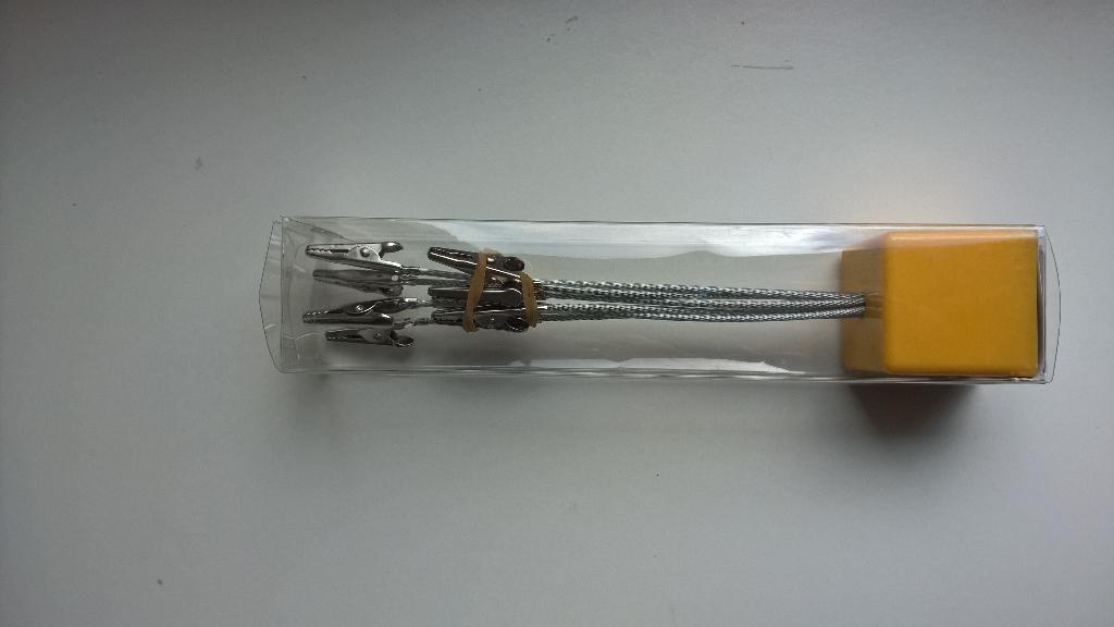 Varen er en såkaldt memoholder, der er ifølge de tilstedeværende oplysninger er sammensat af en terningformet fod af plastik (ca. 4 x 4 x 4 cm) beklædt i bunden med filt. 

I denne terning er fæstnet 8 fleksible stålwirere (diameter 2 mm) af flettet metal-tråd (4 stk. med længde 10 cm og 4 stk. med længde 13 cm.) overtrukket med klart plast.

Metaltråden er for enden forsynet med en krokodilleclips som ifølge oplysningerne er af jern med en blank overflade og med en fjedermekanisme, der udgør en klemme. 

Klemmens funktion er at holde f.eks. et billede, et kort eller en huskeseddel.