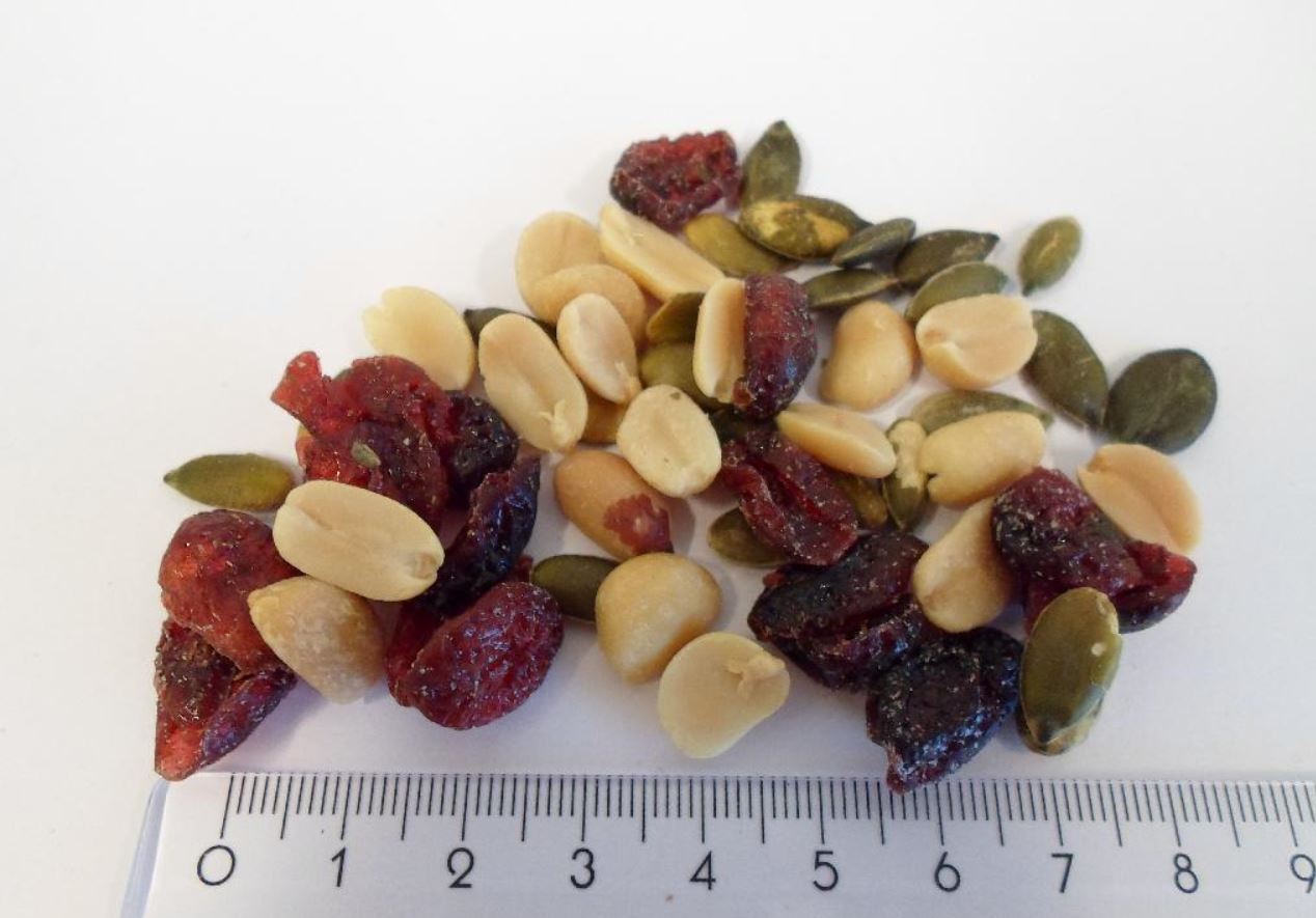 Varen er en fødevare. Varen frembydes i detailsalgspakninger på nettovægt 1 kg og derunder.
Det er oplyst, at varen består af: 
-	45 % økologiske tørristede saltede peanuts
-	30 % økologiske tørristede/saltlage græskarkerner
-	25 % økologiske tørrede tranebær
Jordnødderne i varen er ca. 1,2 cm lange. De er uden den brune hinde, og smager ristede og saltede som jordnødder. 

Græskarkernerne er ca. 1,5 cm lange. Der er en grøn hinde på kernerne, og smagen er en let saltet bitter smag som græskarkerner. 

Tranebærrene er ca. 1,5 til 2 cm lange. Farven varierer fra en klar rød til næsten sort. Smagen er lidt sødlig af tørrede tranebær.