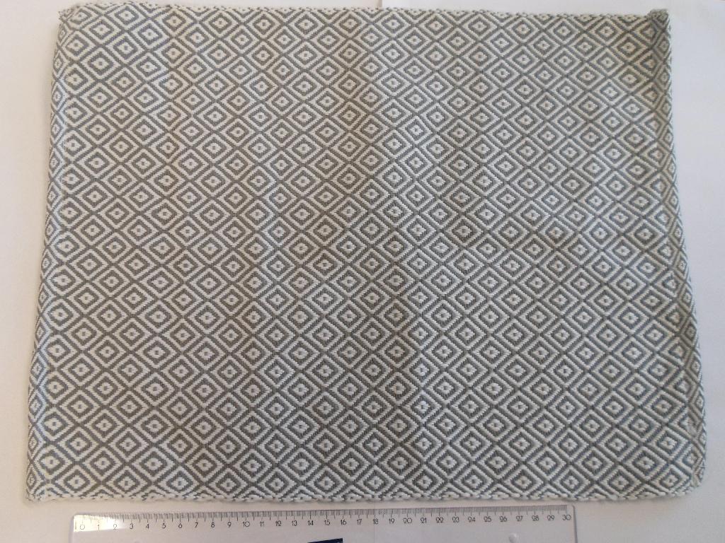 Der er tale om en dækkeserviet, hvis mål er 33 x 44 cm.
Det er oplyst, at varen er fremstillet af 65 % bomuld og 35 % polyester, og den er vævet i et rombeformet mønster. Den fremsendte vareprøve er af garn i gråt og hvidt.

Vægten pr. dækkeserviet er oplyst til at være 70 g/stk. og 510 g/m2.

På to af siderne er der ægkant, og på de to andre, er kanten ombøjet og syet fast. Varen betragtes derfor som en konfektioneret vare.