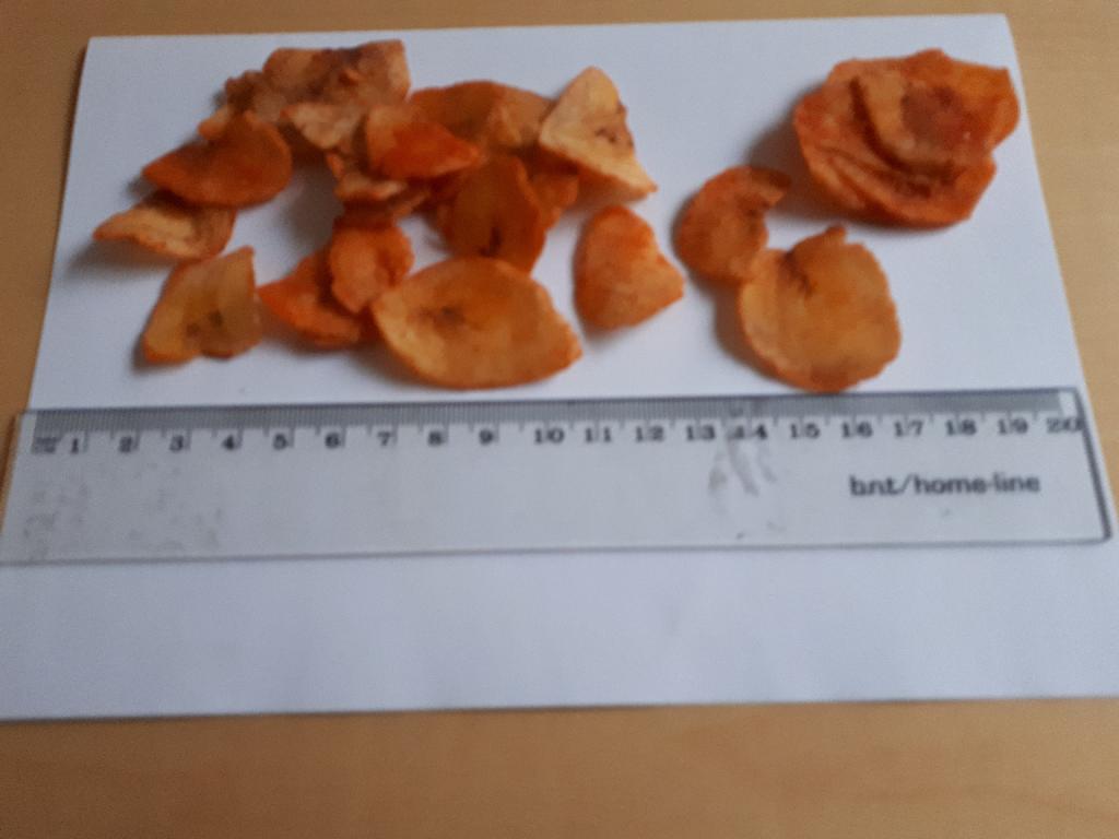 Varen bliver, efter at være skåret i tynde skiver, ristet i kogende vegetabilsk olie. Derefter tilsættes krydderi og varen dyppes i vegetabilsk olie for at sikre at krydderiet sidder fast. Herefter slynges varen for at fjerne overskydende olie. 

Varen fremstår som bananer (Kepok-bananen) i tynde skiver påført krydderiet chili. På grund af krydderiet foreligger de i en rød-orange farve. 

Tykkelsen på skiverne er op til 3 mm. Og de foreligger både som hele og halve skiver. Det er tydeligt at se, at der er tale om bananer, da man i kernen af skiverne kan se bananens frø. 
 
Varen dufter krydret og skiverne føles lettere fedtet og ru af krydderiet. Varen har en let stærk smag af chili og selve banansmagen er ikke særligt fremtrædende.
Varen er en fødevare(bananchips).
Det er oplyst, at varen har følgende indhold: banan, chili, løg, salt, vegetabilsk olie(palmeolie)
Varen frembydes i pakninger af 20 gram og 50 gram.