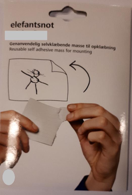 Varen foreligger som en klæbende modellerbar, grålig masse, der er formet som en plade med riller i. Der kan hives stykker af pladen, og disse stykker kan formes, så de passer til det der skal hænges op.
Varen har en kraftig, kunstig duft.
Varen kan bruges til at hænge plakater og billeder op på en væg med.
Ifølge den medsendte produktspecifikation, indeholder varen butylgummi, calcium carbonat og polyisobutylene.
Varen er omsluttet af vokspapir og pakket i detailsalgsemballage. Det er oplyst, at pakken indeholder 40 g og, at emballagen måler 5 x 10 cm.