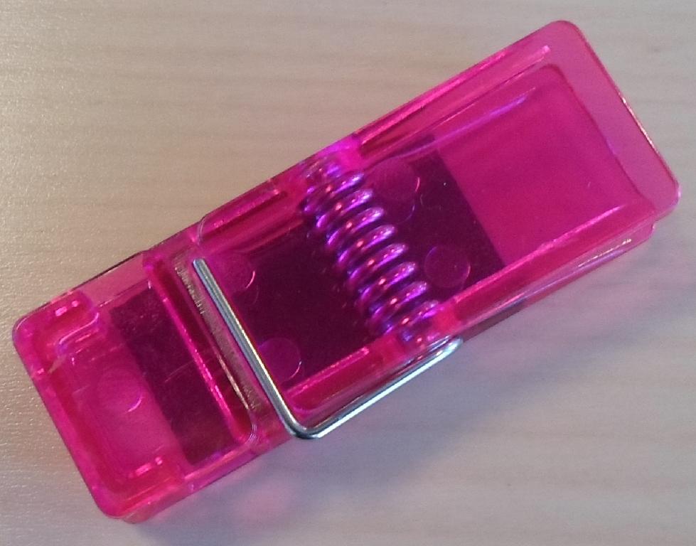 Varen er en plastklemme med fastklæbet magnet.
I klemmen kan placeres huskesedler, diverse papirer eller andet lettere materiale, eller den kan anvendes som en almindelig tøjklemme.
Med magneten kan klemmen placeres på en flade, der tiltrækkes af magnetkraften deri.
Varen består af en klemme i 2 dele af polystyren plast, sammenføjet med en bøjet metalfjeder i rustfrit stål og med en magnet med jernoxid som det magnetiske materiale fastgjort på den ene klemmeflade.
Klemmens mål er ca. 6 cm x 2,1 cm x 1,4 cm.
Magnetens mål er ca. 3,7 cm x 1,8 cm x 0,2 cm.
Plastmaterialet er gennemsigtig og kan foreligge i forskellige farver.