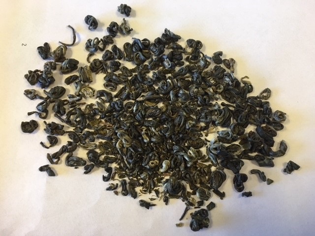 Varen foreligger som tørrede, rullede hele teblade med kuglelignende eller aflang form. Blandingen er mørk (brune og sorte nuancer) med enkelte lysere blade. Varen har en svag duft af halm/græs.
Varen anvendes til fremstilling af te.
Det er oplyst, at varen er fremstillet af ufermenteret grøn te. Teen er håndplukket i hele blade og efterfølgende håndrullet og soltørret.
Det er oplyst, at varen foreligger i løs vægt og indføres i mængder på 3 kg og derunder. Det er oplyst, at varen foreligger i en lufttæt beholder af pap indeholdende en pose af papir, hvori varen er placeret.