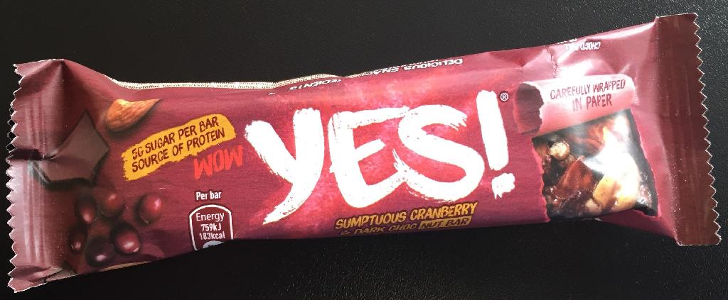 Varen er en frugtholdig nøddebar med chokolade. 
Den foreligger i en papemballage, indeholdende 3 enkeltindpakkede nøddebarer.
Varen foreligger som en fødevare og er klar til direkte fortæring som snack.
Varen er ifølge det oplyste et blandingsprodukt med tranebær, ristede jordnødder, peanødder og mørk chokolade. Den har en markant nøddesubstans, som understøttes af en chokoladebund.
Der angives følgende ingredienser i varen: 30 % mandler, 26 % ristede jordnødder, 11 % mørk overtrækschokolade, cichorierodsfiber, 2 % tørrede tranebær, dekstrin, sprøde sojastykker, honning, glukosesirup, kakaomasse, emulgator, aroma.
Næringstabellen angiver følgende indhold: 34,1 % fedt, 25,4 % kulhydrater heraf 13,8 % sukkerarter, 16,5 % fibre og 20,3 % protein.
Baren indeholder halve jordnødder, små stykker af nødder eller lignende og hele mandler/overskårne mandler og få røde bær. Baren hænger ikke fast sammen, den kan let deles i mindre stykker med hånden, og den trækker da tynde tråde.
Baren smager af nødder og chokolade.
Varen foreligger i papemballage, indeholdende 3 barer med en samlet nettovægt på 105 g (3 x 35 g). 
En bar måler ca. 9,5 x 2,7 x 1,5 cm.