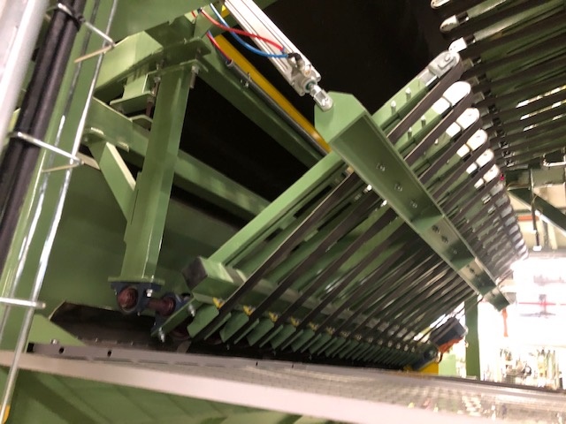 Varen fremstår som en maskine, der benyttes sammen med andre elementer i et industrianlæg. Maskinen er oplyst som en remtransportør med en vippe-funktion.

Transportøren skifter mellem to positioner (op/ned) ved hjælp af en mekanisk arm, der drives af enten en gearmotor med en krumtap eller en cylinder.

Remmene er monteret på en stålramme og drives af en elektrisk motor.

Stålrammen er fæstet med lejer i den ene ende, der giver mulighed for vippe-funktionen.
Det er oplyst, at varen benyttes til at transportere produkter videre gennem et større industrianlæg.

Varen kan transportere produkterne til to forskellige destinationer ved hjælp af vippe-funktionen.
Virksomheden oplyser, at varen har en længde på 2 meter og en bredde på 2,6 meter.