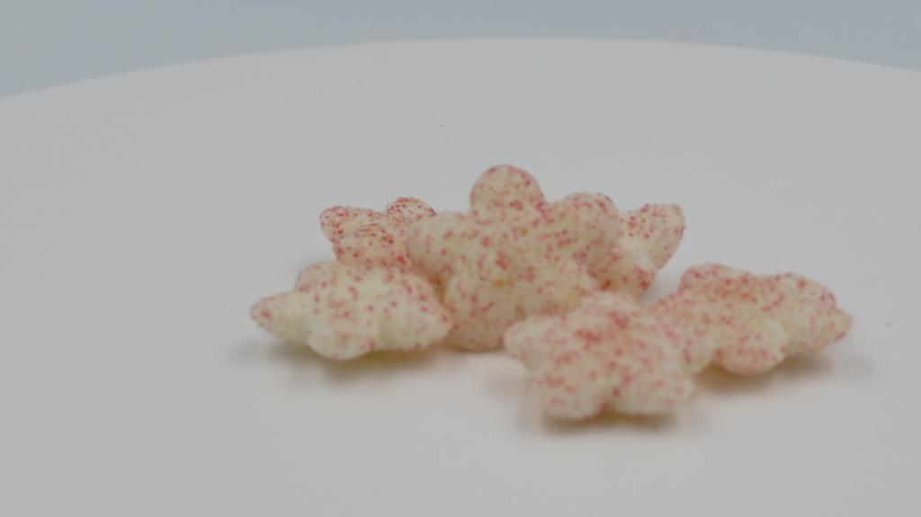 Varen foreligger som små, hvide blomster med pinkfarvede prikker på ydersiden, pakket i en cylinderformet metaldåse med plastlåg.

Varen knaser og smager svagt af hindbær og banan. Varen har en markant smag af ris og lidt af hvede.
Efter det oplyste anvendes varen som en sund snack til babyer fra 8 måneder.
Det er oplyst, at varen består af rismel, hvedemel, solsikkeolie, banan, hindbær, surhedsregulerende middel, vitamin og antioxidant.

Næringstabellen angiver indhold af fedt, kulhydrater, heraf også sukkerarter, kostfibre, protein, salt og thiamin.
Varen foreligger i detailsalgsemballage med en nettovægt på 35 gram.