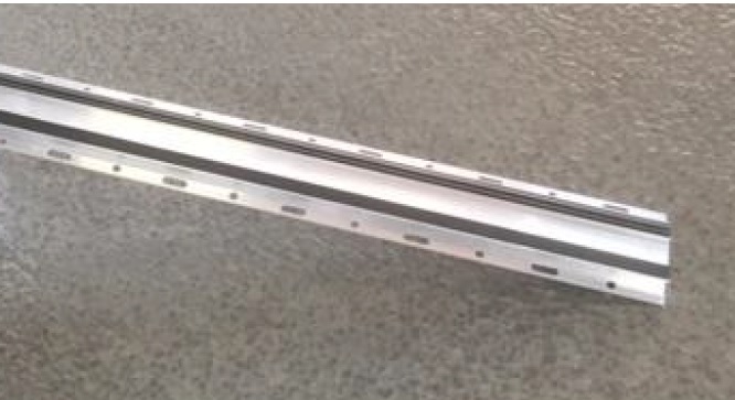Varen er en aflang skinne af aluminium. I hver side af skinnen sidder der huller i hele skinnens længde. Hullerne er skiftevis runde og ovale. På skinnens overside sidder der to gummibånd i hele varens længde.
Det er oplyst, at varen anvendes som beslag til murkrone-inddækning på tagets murkrone. De to gummilister tætner op mod murkronen.
Det er oplyst, at varen består af legeret aluminium. 

Det fremgår af det modtagne materiale, at de to gummibånd er monteret vha. dobbeltklæbende tape.
Det fremgår af det modtagne materiale, at varen foreligger med følgende mål:
Længde: 5000 mm
Bredde: 87 mm
Højde: 14 mm