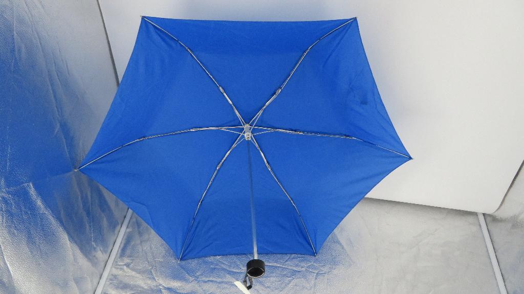 Varen er en paraply, med sammenskydelig teleskopskaft og en sammenklappelig skærm. Varen har et kort plasthåndtag, der er åbent i enden op mod paraplyen, og hvorpå der er fastgjort en strop. Når paraplyen er klappet sammen, kan håndtaget beskytte eller fastholde paraplystellets spidser.
Paraplyens skærm er fastgjort på et foldbart stativ, og har en lille strop fastgjort, som ved hjælp af burrebånd kan lukkes rundt om skærmen, når den er klappet sammen.
Varen kan i udfoldet tilstand beskytte mod vejret. Da varen kan klappes sammen, er det muligt at opbevare den i en taske eller lignende.
Det er oplyst, at varens sammenklappelige stel er lavet af aluminium og glasfiber, den konfektionerede skærm er lavet af tekstil af polyester, mens håndtaget er lavet af ABS plast.
Varen er i sammenklappet tilstand ca. 23 cm lang og 4,5 cm i diameter.
Når paraplyen er stået op, er den ca. 89 cm i diameter, og ca. 51 cm høj.
Varen findes i forskellige farver og mønstre.