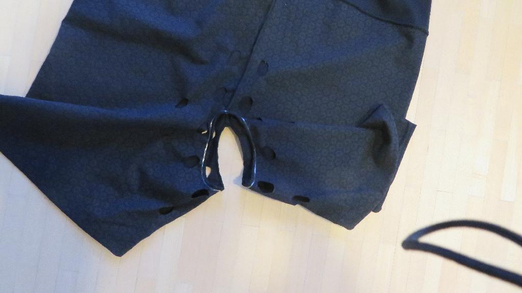 Varen foreligger som en elastisk beklædningsgenstand med korte ben fremstillet af trikotagestof. Varen er udformet som såkaldte womens briefs. Mellem buksebenene, i skridtet, er der et stort hul, der går lidt ned af hvert bukseben. Rundt i hullets kant er der påsyet et smalt bånd bestående af et gennemsigtigt, elastisk materiale.

På forsiden af varen er der lavet 8 huller på hvert ben. Tilsvarende huller findes på varens bagside. 

På buksebenenes stof er der et mønster af matte, sekskantede figurer. Mønsteret er lavet af et gennemsigtig gummiprint.
 
Varen har en ca. 8 cm bred kant rundt i det øverste stykke. Kanten består af 2 lag elastikstof.
Det er oplyst, at varen er beregnet til fastholdelse af forbindinger, i skridtet og på ballerne.
Ifølge det modtagne materiale består varen af Micro Modal og elastan.
Varen foreligger i detailsalgsemballage, og findes efter det oplyste i sort, i størrelserne S til 2XL.

Linning ca. 8 cm, benlængde ca. 14 cm, sidelængde ca. 35 cm for en str. L.
