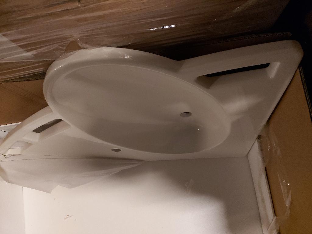 Varen er en håndvask og bordplade støbt i ét. Håndvasken er oval og placeret i den ene side af bordpladen. Bordpladens dybde er større i den ene side end den anden, og vasken er støbt i den dybe side. 
Kanten af bordpladen går i en bue, hvor den ovale håndvask bryder ud af buen. Langs det yderste af bordpladen er der tre firkantede huller i bordpladen. Disse udgør håndtag. 

Varen kommer som bordplade med en højre eller venstre vendt håndvask.
Varen fungerer og anvendes som en håndvask og bordplade. Bordpladens håndtag giver mulighed for støtte til fx kørestolsbrugere.
Det er oplyst at varen består af støbt polyester, der er coatet med hård gel. Ifølge det modtagne materiale består coatingen af polyester resin.
Det er oplyst, at varen kommer uden monteringer af nogen art.