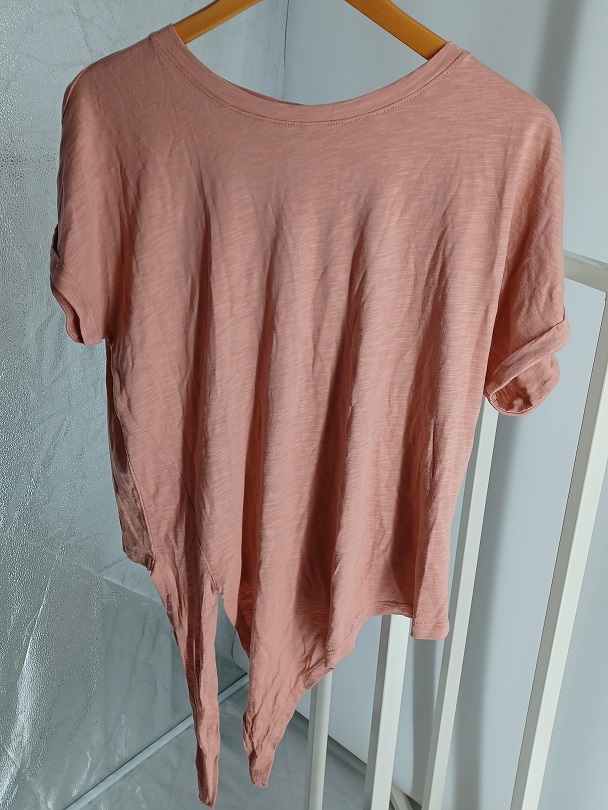 Varen er en beklædningsgenstand beregnet til at bæres på overkroppen, som en T-shirt. Den er løstsiddende med korte ærmer. Den har en let rund og nedringet halsudskæring, med et påsyet kantbånd. Varen er designet med to lange snipper, nederst i højre side. Ærmerne har et lille opsmøg.
Varen er beregnet til at kunne bæres på overkroppen som en T-shirt.
Varen er fremstillet af trikotage, bestående af 50 % bomuld og 50 % modal.
Varen fås i forskellige størrelser. Den foreviste vareprøve er i størrelsen medium

Tekstilstoffet fremtræder som et let tekstilstof, der typisk anvendes til T-shirts.