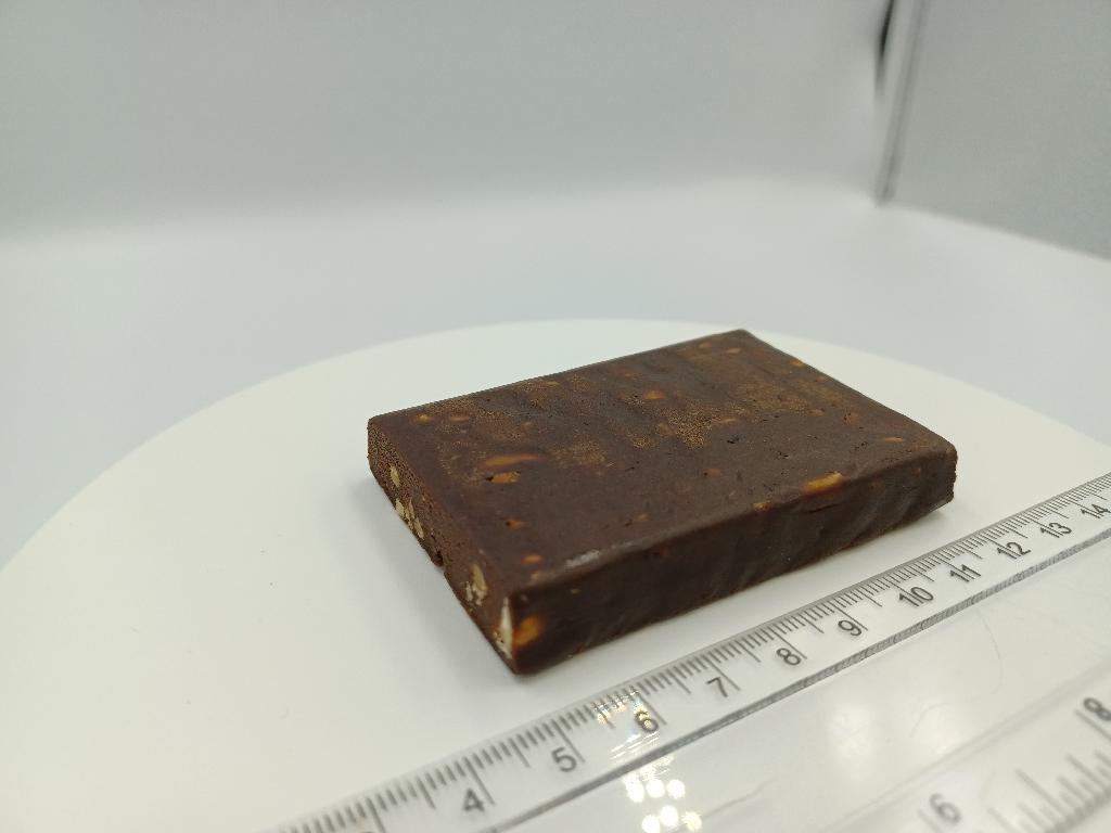 Varen er en brun, firkantet plade med synlige stykker af jordnødder. Varen smager sødt og af kakao, dadler og saltede jordnødder.
Varen er en fødevare og kan spises som en snack.
Efter det oplyste består varen af følgende ingredienser: 
Dadler, tørret æggehvide, kakaomasse, jordnødder, naturlig aroma og havsalt.
Varen måler 1x5x7 cm og foreligger i detailsalgspakninger med en nettovægt 55 gram.