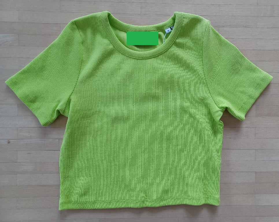 Varen er en såkaldt crop top – en kortærmet trøje, der i længden går til over taljen. Varen har en tætsiddende, rund halsudskæring med påsyet kant af samme stof som resten af trøjen. For enden af ærmerne og i bunden af trøjen, er stoffet ombøjet og fæstnet med en dobbelt syning.
Varen er lavet af ribstrikket trikotagestof.
Varen er en beklædningsgenstand beregnet til at blive båret på overkroppen.
Det er oplyst, at tekstilmaterialet er 2x2 rib og er lavet af 95 % bomuld og 5 % elastan.
Ifølge det oplyste fås varen i størrelse XXS – XXXL og er beregnet til detailsalg.
I størrelse S er ryglængden ca. 39 cm.
Varen er ensfarvet og fås i forskellige farver.