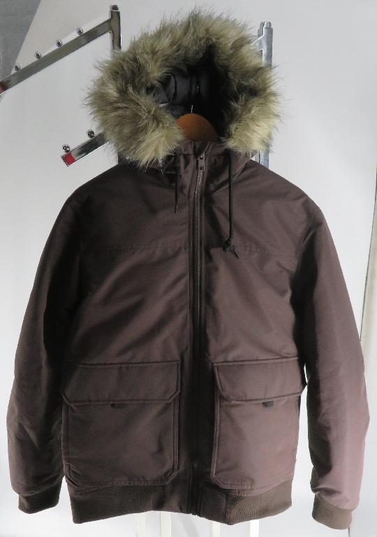 Varen er en beklædningsgenstand til overkroppen, som går til hoften, med gennemgående lynlås-lukning foran. Ved kanten af kraven er der et lille overlap, som går højre over venstre. Varen har hætte med pelskrave og snor i kanten af hætten til sammentrækning. Foran er der placeret to lommer med knaplukning. Nederst på varen, samt nederst på begge ærmer, har varen ribkant. På indersiden har varen et vatteret for.
Det er oplyst, at varen anvendes som en overtøjsjakke til herrer. Varen er beregnet til at beskytte mod vejret.
Ifølge oplysningerne er varen fremstillet af tætvævet polyester.
Varen kan foreligge i flere forskellige farver.