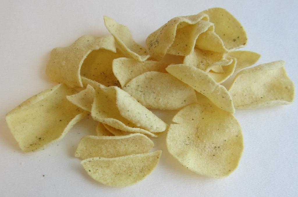 Varen er lysegule chips med en rund, ujævn form. På overfladen ses et lyst pulver med små grønne bestanddele. Varen har en tør og sprød konsistens. 
Varen dufter lidt krydret og af olie og smager lidt syrligt og af løg.
Varen er en fødevare.
Det er oplyst, at varen består af kartoffelpulver, kartoffelstivelse, vegetabilske olier, salt, løgpulver, vallepulver, kærnemælkspulver, sukker, syre, persille, gærekstrakt, hvidløgspulver, creme fraiche pulver, farvestof, naturlig løgaroma. 
Det er oplyst, at varen er lavet af en dej, der er ekstruderet, tørret og fritteret.
Den fremsendte vareprøve er pakket i uigennemsigtig detailsalgsemballage indeholdende 140 gram.