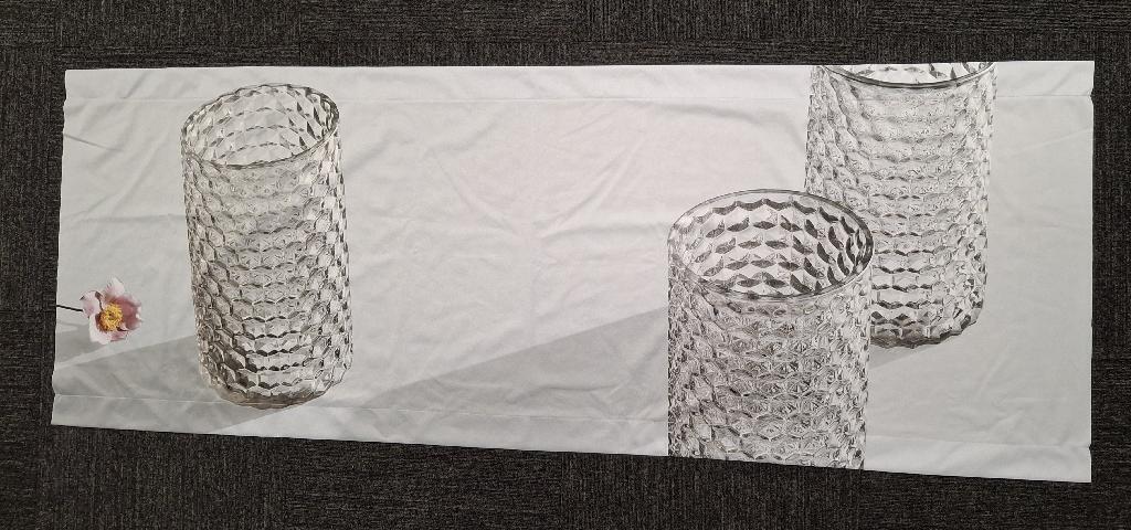 Varen er et trykt, aflangt stykke tekstilstof med en syet løbegang for oven og for neden. På varen er der trykt et billede af tre mønstrede drikkeglas og en blomst.
Det er oplyst, at varen skal anvendes til reklame.
Varen er lavet af trikotagestof, der ifølge det oplyste er af polyester.
Varen måler ca. 65 x 175 cm. Løbegangene er ca. 5 cm brede.