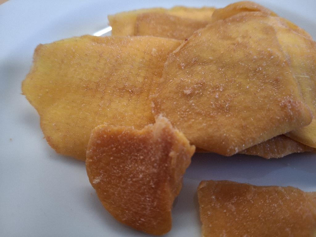 Varen er flade, uensartede stykker af tørret mango. Mangostykkerne er orange og har en ru overflade med lidt rødligt pulver. Varen dufter sødt af mango og smager sødt af mango med en meget mild smag af jordbær.
Varen er en fødevare, der kan spises som den er.
Varen er tørret mango med jordbærsmag og består af mango, sukker, jordbærpulver, naturlig jordbæraroma, surhedsregulerende middel (citronsyre) og konserveringsmiddel (natriumdisulfit).
Varen foreligger i detailsalgspakninger med en nettovægt på 100 g.