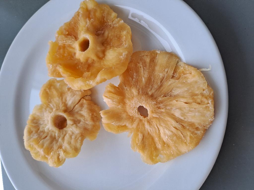 Varen er gule, tørrede skiver af ananas. Skiverne er bløde i konsistensen og har varierende størrelser og tykkelser. De er delvist dækket af et fint hvidt pulver. Varen dufter og smager syrligt og sødt af ananas.
Varen er en fødevare. Ifølge oplysningerne på emballagen er varen spiseklar.
Af emballagen fremgår det, at varen består af ananas, sukker, surhedsregulerende middel og konserveringsmiddel.
Den modtagne vareprøve foreligger i detailsalgsemballage med en nettovægt på 100 gram.