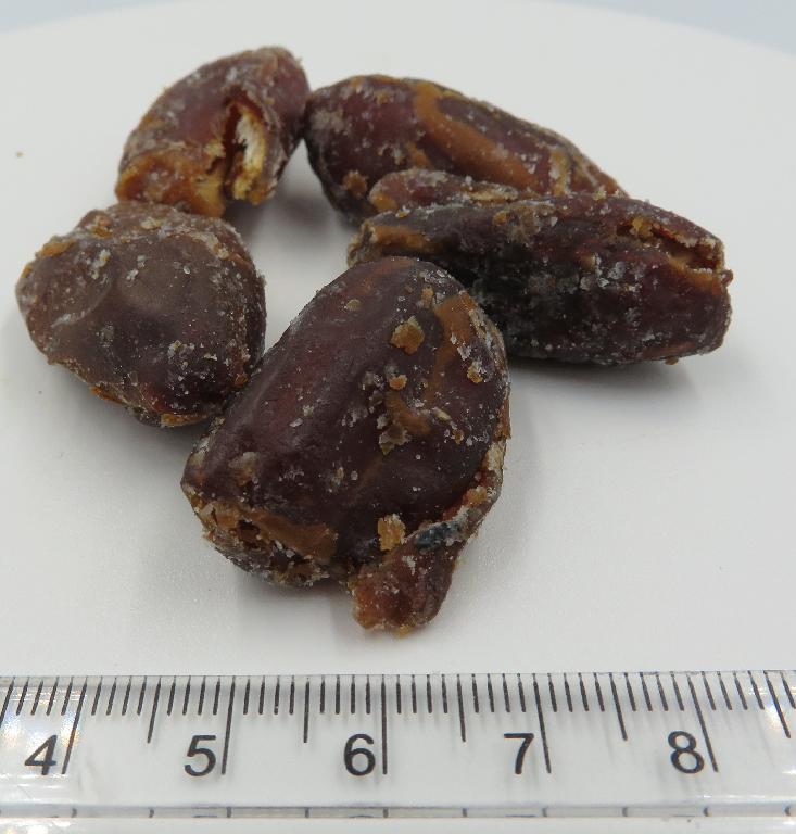 Varen består af hele, tørrede, udstenede dadler med et tyndt lag af en hvid-/brunlig belægning på ydersiden. De dufter sødt af karamel, har en sød smag af dadler og karamel samt salt på ydersiden. Konsistensen er blød og sej.
Varen er en fødevare, der kan spises som den foreligger.
Det er oplyst, at varen består af udstenede dadler, aroma (karamel, salt) og kokosolie.
Varen er pakket i detailsalgsemballage indeholdende 100 gram nettovægt.