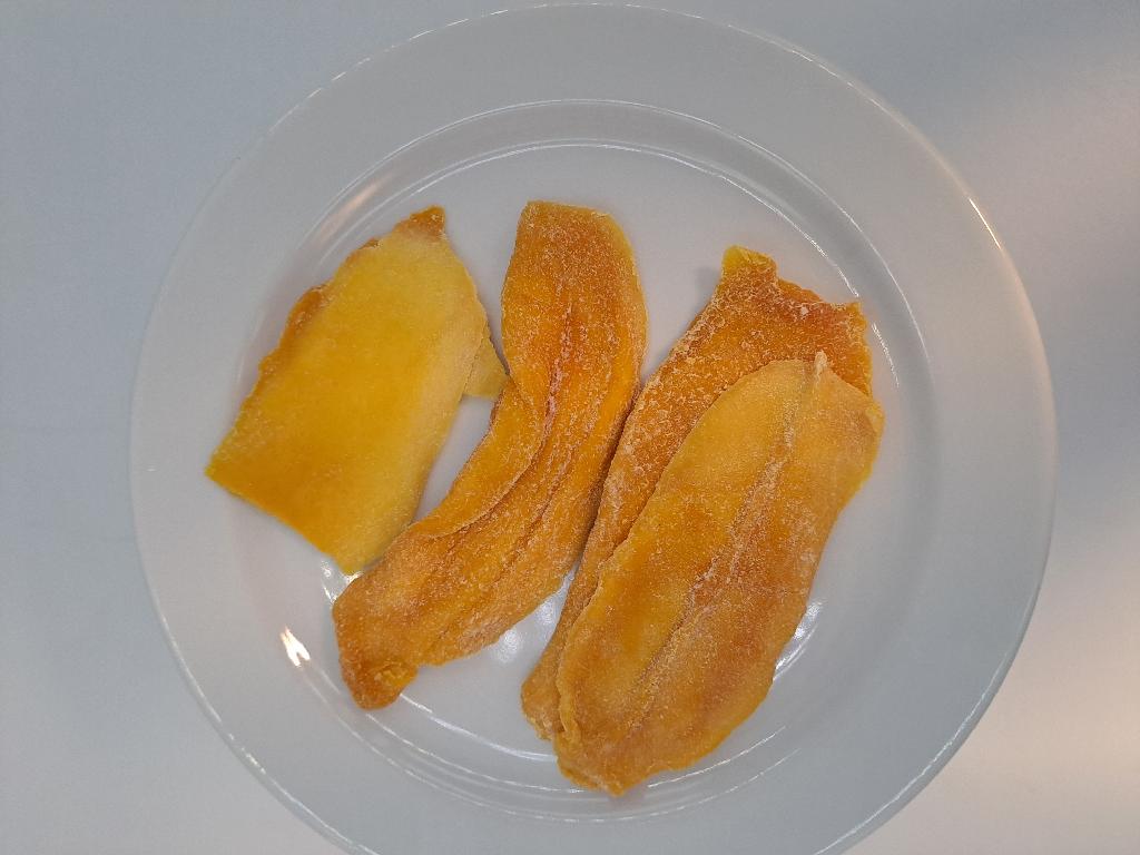 Varen er orange/gule skiver af tørret mango med fine hvide krystaller i overfladen. Skiverne er bløde i konsistensen og har varierende størrelser og tykkelser. 
Varen dufter og smager syrligt og sødt af mango.
Ifølge oplysningerne på emballagen er varen spiseklar.
Af emballagen fremgår det, at varen består af mango, sukker, surhedsregulerende middel og konserveringsmiddel.
Den modtagne vareprøve foreligger i detailsalgsemballage med en nettovægt på 100 gram.