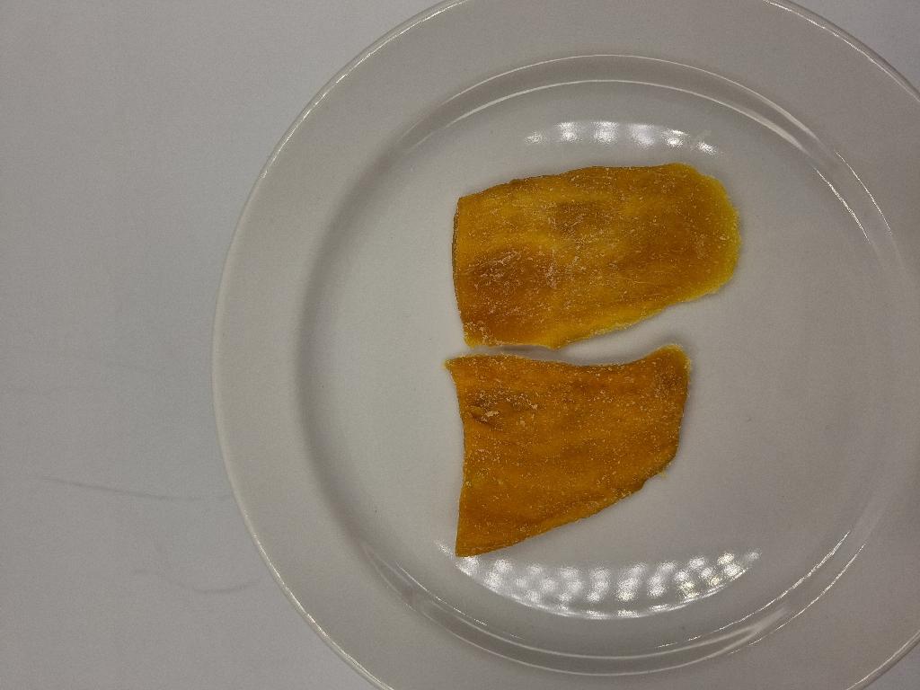 Varen er flade uensartede stykker af tørret mango. Mangostykkerne er orange med hvidt pulver. Varen har en sød smag af ananas, mango og kokos og en sød duft af kokos og ananas.
Varen er en fødevare og kan spises uden yderligere tilberedning.
Varen er tørret mango med kokos- og ananassmag og består af mango, sukker, ananaspulver, kokosnødspulver, naturlig aroma (ananas og kokosnød), antioxidant (citronsyre), konserveringsmiddel (natriumdisulfit).
Varen er pakket i detailsalgsemballage med nettovægt på 100g.