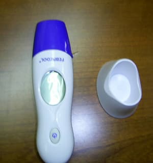 Termómetro electrónico para uso clínico que funciona por infrarrojos y que incorpora un reloj eléctrico en la misma envoltura. En la parte frontal dispone de un botón para el encendido y de una pantalla para visualizar la temperatura o la hora. Se presenta para su venta al por menor en una caja con una pila de litio, un manual y una base de plástico para sujetarlo