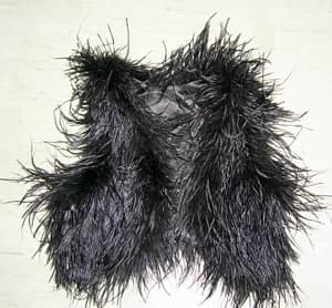 Chaleco de plumas de avestruz que cubre la parte superior del cuerpo hasta por encima de la cintura, sin mangas, abierto completamente por delante, sin cierre. Con forro de tejido de trama y urdimbre de fibras sintéticas (poliéster). De color negro.