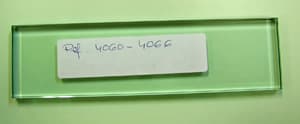 Placa rectangular de vidrio bisela en los bordes y pulida en los cantos, con unas medidas de 284 x 45 x 8 mm que se utiliza como base para la fabricación de trofeos.