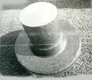 Semiproducto de acero aleado con un contenido de carbono entre el 0,42 y el 0,5 %. Tiene la forma de un cilindro con un diámetro exterior de 70 mm, una altura de 190,1 mm y se ensancha por un lado en forma troncocónica de 44,1 mm de altura. Se obtiene por forja sin matrices y para su utilización final necesitan de operaciones complementarias de mecanización.