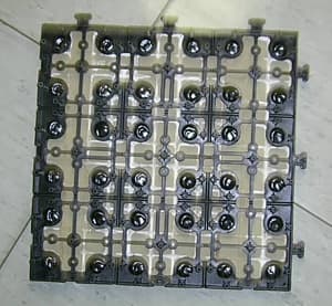 Baldosa de pizarra con unas medidas de 295 x 295 x 12 mm, compuesta por cuatro losetas de 145 x 145 mm que se presentan pegadas sobre un soporte de plástico. Las losetas de pizarra han sido obtenidas por aserrado y el soporte de plástico tiene una altura de 17 mm y en los laterales tiene lengüetas e hendiduras para facilitar su montaje.