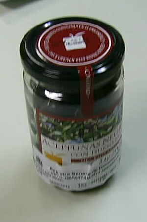 Preparación alimenticia a base de aceitunas negras maceradas con agua y sal. Se presenta en envasada, sin líquido y acondicionada para su venta al por menor al consumidor final, en recipientes de cristal con tapa de metal y 180 gramos de contenido neto, que experimentan un proceso de pasteurización.
