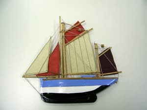 Artículo decorativo que por su parte delantera representa un barco velero y que presenta plana su parte posterior en la que incorpora dos pequeños imanes circulares que tienen por objeto fijarlo a una superficie metálica. Se presenta con unas dimensiones máximas aproximadas de 17 cm de longitud por 16 cm. de alto y está elaborado con madera (distinta de las mencionadas en la nota complementaria 2 del capítulo 44), tejido, hilados, imanes y unos pequeños enganches metálicos, siendo la madera la materia que conforma el cuerpo del barco y que predomina en cantidad.