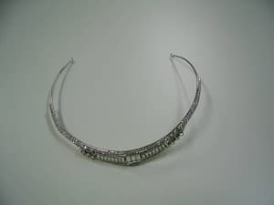 Pasador metálico (hierro) que incorpora adorno de plumas (poliéster) y dos perlas de plástico. El adorno se sujeta al pasador con dos alambres metálicos.
Es utilizada por las mujeres para adorno y para asegurar el peinado.