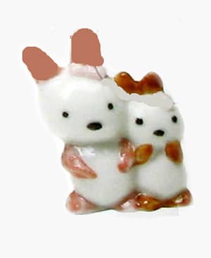 Figura de 3 cm que simula a una pareja de conejitos con un lazo en la cabeza. Está decorada con tres colores (orejas, patas, boca y ojos) y fabricada de porcelana. Se destina a servir de regalo sorpresa en el interior de productos de pastelería en la fiesta de reyes.
