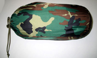 Saco de dormir abierto con capa exterior e interior de poliamida y relleno de poliéster. Estampado de camuflaje. Viene con una funda de almacenaje de poliamida cuyo extremo está cerrado mediante un cordón y una "tanka".
Pespunteado para sujetar las dos capas con el relleno. Cierre mediante cremallera en dos de sus lados, lo que permite su apertura completa y uso como cobertor.