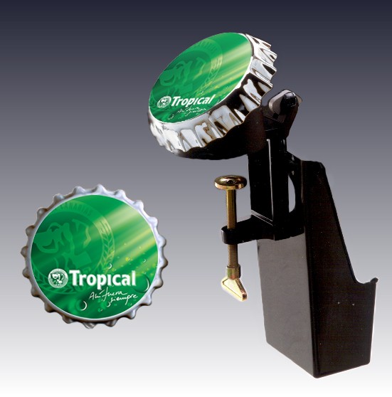 Abrebotellas de metal diseñado para fijarse en una barra de bar. Se presenta desmontado y  consta de tres partes, el cuerpo abridor, un deposito para chapas, y un soporte publicitario.
 1.El abridor, de aluminio inyectado, incluye un tornillo de fijación. Constituye la parte operante del abrebotellas. 
 2.El soporte publicitario consiste en  una chapa de plástico de gran dimensión que imita al tapón de una botella.
 3.El depósito para recogida de chapas se atornilla en el cuerpo del abridor.