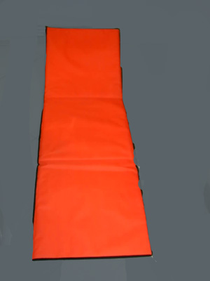 Colchoneta plegable formada por un tejido exterior de poliéster y un relleno de espuma de poliestireno de 7 mm. de grosor. Presenta todo su contorno ribeteado, un bolsillo con cierre de cremallera en una de sus caras e incorpora una estructura de tubos metálicos, en uno de sus extremos, que permiten mantenerla parcialmente erguida para poder apoyar la cabeza y la espalda así como un asa para facilitar su transporte.