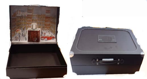 Caja de cartón rígido y liso (26,5 x 21,5 x 10,5 cm.) sin elementos interiores de distribución, sin bisagras ni sistema de cierre. La tapa se abre manteniendo unida al resto de la caja su lado posterior y presenta un asa de poliuretano, refuerzos metálicos en sus esquinas y una lámina decorativa en relieve en una de sus caras internas. Según declaración del solicitante se utiliza para contener productos cosméticos destinados a la venta.