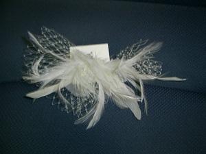 Pasador metálico (hierro) que incorpora adorno de plumas (poliéster) y dos perlas de plástico. El adorno se sujeta al pasador con dos alambres metálicos.
Es utilizada por las mujeres para adorno y para asegurar el peinado.