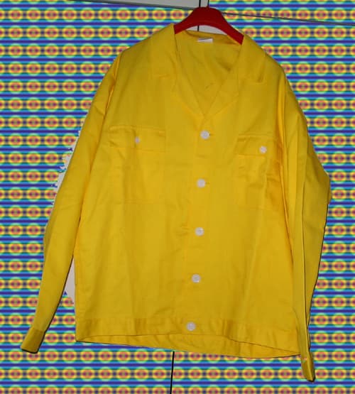 Prenda de vestir, color amarillo, confeccionada con tejido de trama y urdimbre (65% poliester, 35% algodón). Cubre la parte superior del cuerpo hasta las caderas, rematadas con una tira al bies, mangas largas con forro que cierra con un bilon. Abertura completa en el delantera que cierra de izquierda a derecha con 5 botones, cuello de solapa. Dos bolsillos a la altura del pecho con una tapilla que cierra con un botón. Costura sobrepuesta en mangas laterales. Cuello camisero enV
