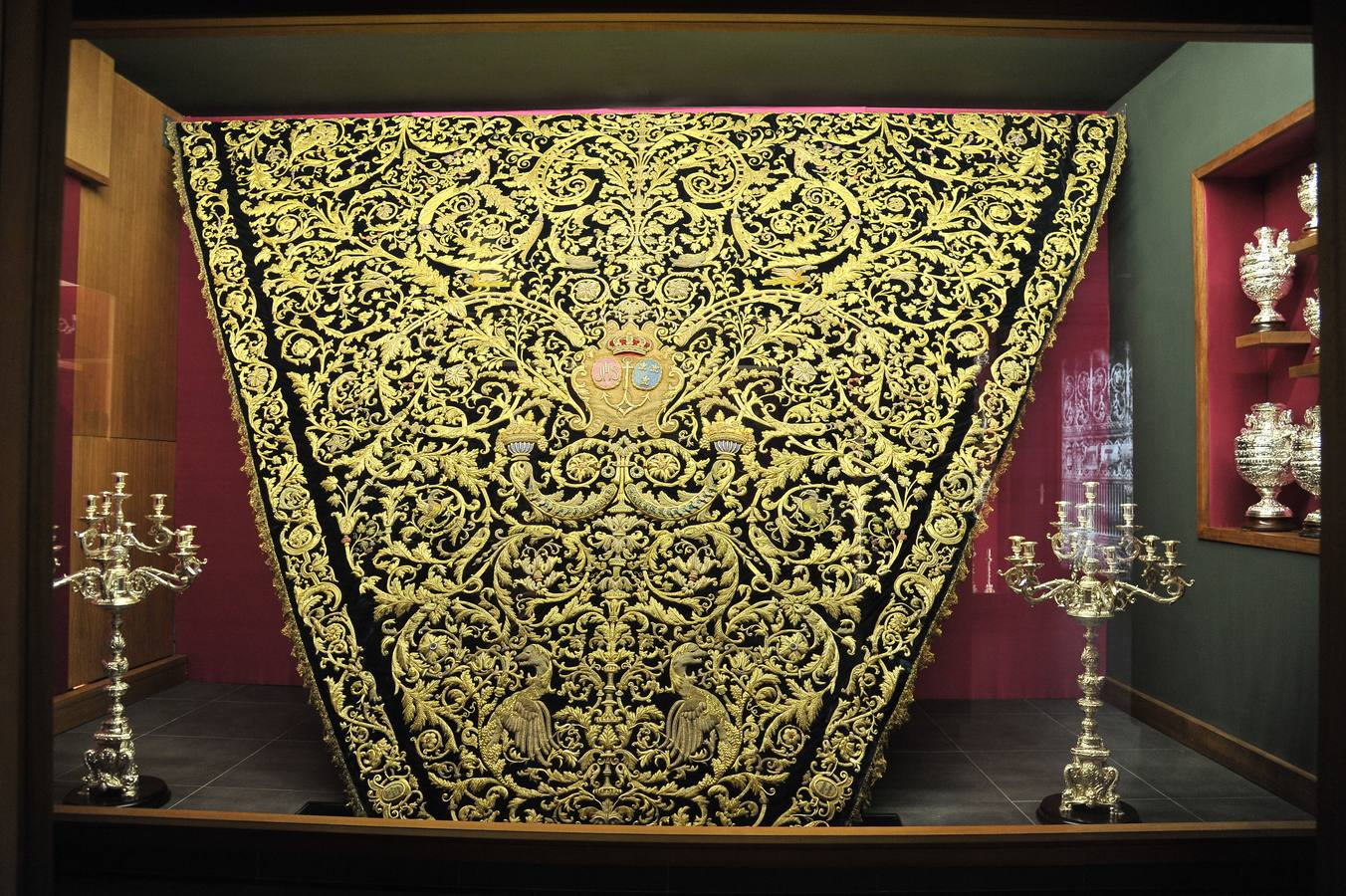 Tapiz tejido a mano consistente en un manto de Virgen que incorpora bordados con hilo de oro. Esta realizado sobre un terciopelo o tejido base en el que irá confeccionada la prenda sobre un bastidor, atirantado de nuevo con un tejido de lienzo moreno.
El bordado se realiza con hilo de oro, se utiliza hilo de seda amarillo para sujetar las puntadas del hilo de oro.  El tejido base es de terciopelo de seda natural.
Diseño original y único. Los trabajos pueden durar un par de años, realizados por varias personas