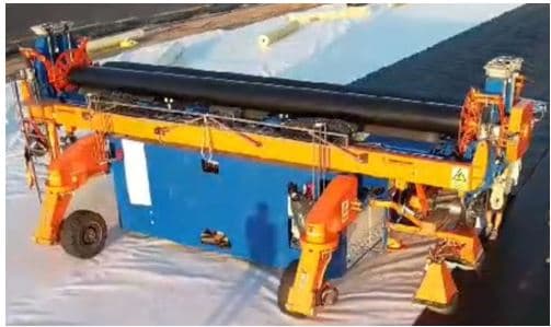Máquina autopropulsada accionada con motores eléctricos y que dispone de un generador ubicado en su interior.

Se trata de una máquina automatizada diseñada para el despliegue de bobinas de materiales geosintéticos en campo abierto (obras de construcción de vertederos, de lagos, de balsas de agua, de lagunas artificiales, de balsas de decantación de minas, etc.) con el objetivo principal de formar una barrera de contención. Pudiendo utilizarse también para desplegar barreras de materiales geosintéticos con el fin de separar materiales, refuerzo del terreno, filtración, etc.

Dispone de cuatro ruedas, rodillos en su parte superior, etc. y sus dimensiones máximas son de aproximadamente 11.439 x 3.725 x 3.297 mm.