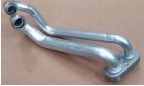 Artículo de aluminio compuesto por una brida de perfil curvo de la que sobresalen dos tubos curvos con recorrido en paralelo de un diámetro aproximado de entre 12 y 16 mm (diámetros diferentes para cada tubo) y un grosor de pared de aproximadamente 1 mm. Este artículo formará parte del sistema de aire acondicionado (HVAC) de un vehículo. 
Se presentan en caja de cartón con entre 40 y 60 unidades.
Según declaración del solicitante por este artículo circulara el líquido refrigerante de un sistema de aire acondicionado de un vehículo automóvil.
