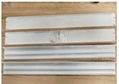 Conjunto de cuatro perfiles metálicos lacados en blanco mate que se ensamblan y conforman el marco de un panel de iluminación superficial para anclar en el techo (la fuente de luz no es objeto de esta IAV).
Presenta unas dimensiones aproximadas de: 60 x 60 x 6 cm, 120 x 30 x 6 cm y 120 x 60 x 6 cm según el modelo. 
Los perfiles están fabricados en aleación de aluminio de la serie 6000 con las siguientes proporciones de los principales elementos aleantes: Magnesio (0,5% en peso), Silicio (0,1% en peso) y Hierro (0,1% en peso).
El artículo se presenta junto con los tacos, los tornillos para su instalación y el manual con instrucciones de montaje.