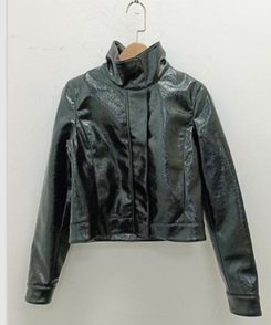 Según declaración del solicitante se trata de una cazadora. Cubre la parte superior del cuerpo y desciende hasta la cintura. Tiene una abertura completa delantera que se cierra con cremallera. Presenta cuello alto y mangas largas. Dispone de dos bolsillos perpendiculares delanteros ocultos en la costura y sin sistema de cierre. A la altura del pecho tiene un ribete imitando un bolsillo, meramente de adorno. Está concebida para ser llevada encima de otra prenda.
Se utiliza como prenda de vestir.
Está confeccionada en plástico celular (poliuretano), con un tejido base y forro, ambos, 100% poliéster. La capa textil es un mero soporte que no ha sido sometido a trabajos más avanzados.