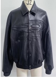 Según declaración del solicitante se trata de una cazadora. Cubre la parte superior del cuerpo y desciende hasta la cadera. Tiene una abertura completa delantera que se cierra con seis botones a presión. Se confecciona con cuello camisero y mangas largas. Presenta un tejido en canalé elástico en puños y bajo, que ajustan la prenda al cuerpo. Dispone dos bolsillos delanteros ribeteados y otro interior, todos sin sistema de cierre. Está adornada con aplicaciones y bordados en el pecho. Está concebida para ser llevada encima de otra prenda.
Está confeccionada en plástico celular (poliuretano), con un tejido base 100% viscosa, relleno y forro 100% poliéster. La capa textil es un mero soporte que no ha sido sometido a trabajos más avanzados.