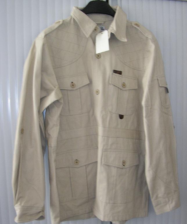 VESTE POUR HOMMES EN TISSU DE COTON, DESCENDANT SOUS LES HANCHES, AVEC DES MANCHES LONGUES, SE FERMANT GAUCHE SUR DROITE AU MOYEN DE BOUTONS, AVEC UN COL, AVEC DES OUVERTURES À L'EXTRÉMITÉ DES MANCHES SE FERMANT PAR BOUTON, AVEC UNE FENTE DANS LE DOS.

L'ARTICLE PRÉSENTE DES POCHES PLAQUÉES AU NIVEAU DE LA POITRINE, SOUS LA TAILLE AINSI QUE SUR LE BRAS GAUCHE, DES PATTES BOUTONNÉES SUR LES ÉPAULES.